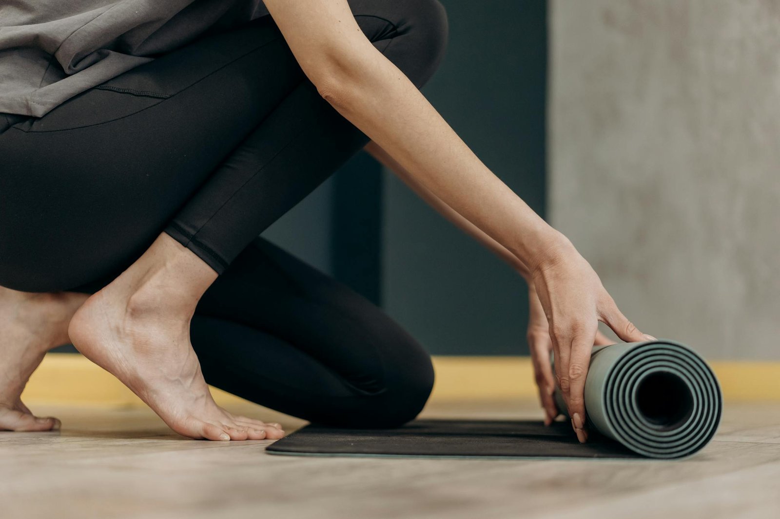 A woman rolling out a yoga mat for an indoor fitness routine, emphasizing calmness and focus.